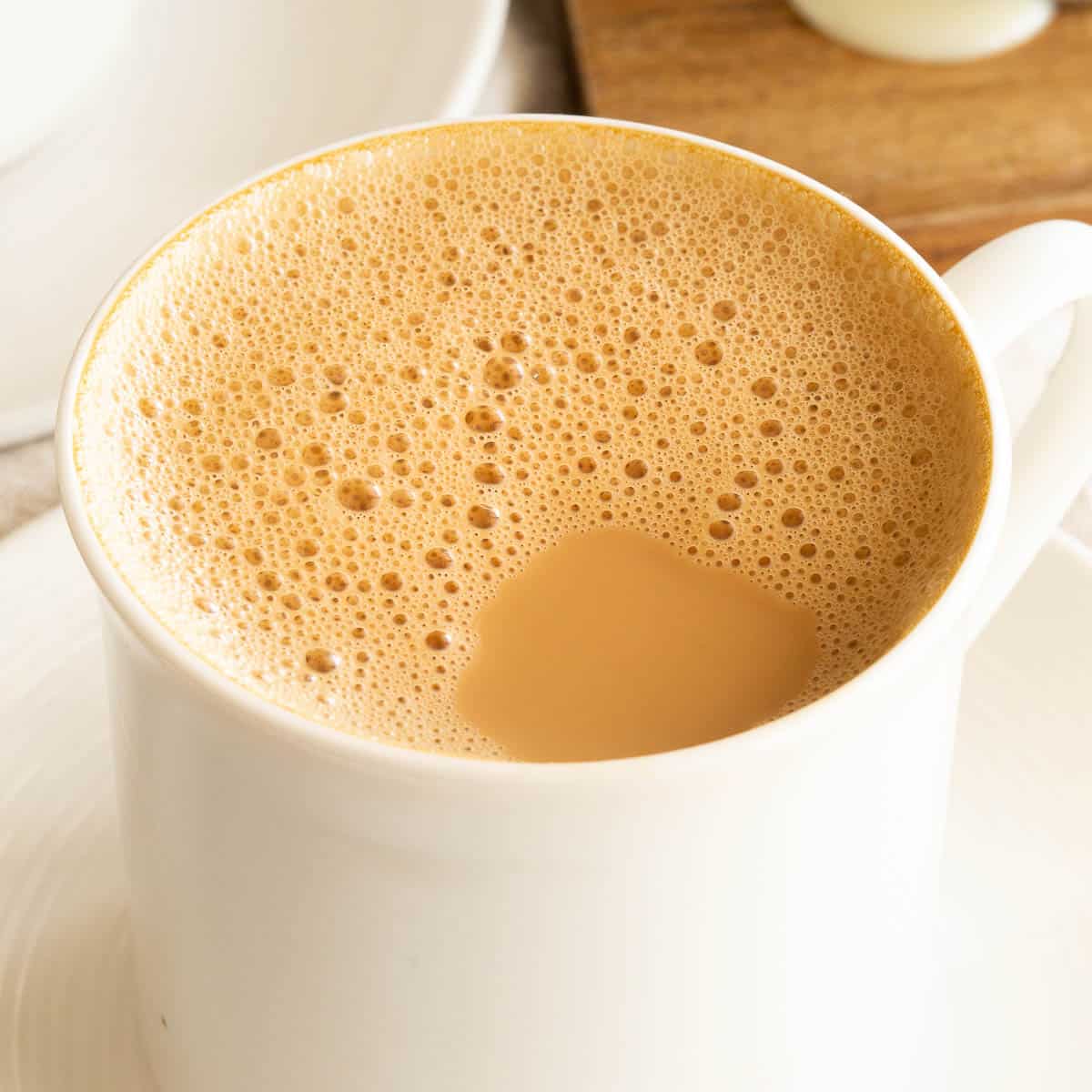 Close up shot of Malaysian pulled coffee in a white mug showing the frothy bubbles on top.