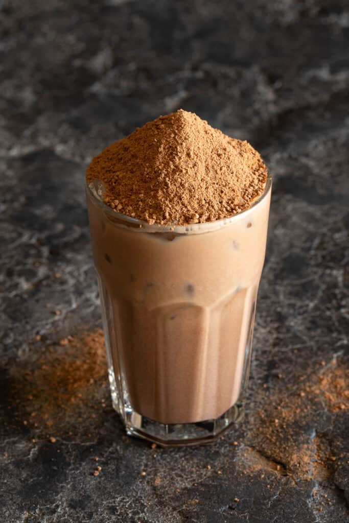 A glass is filled with iced Milo and topped with more Milo powder.