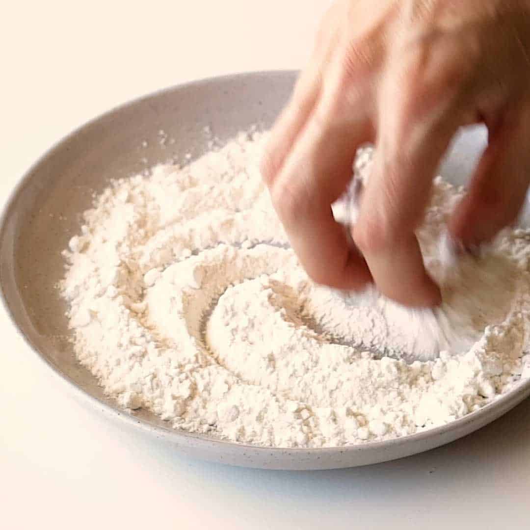 Mixing salt and pepper into the flour.