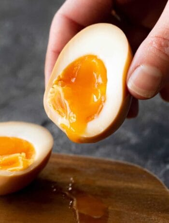 A jammy ramen egg half, held up by a hand.
