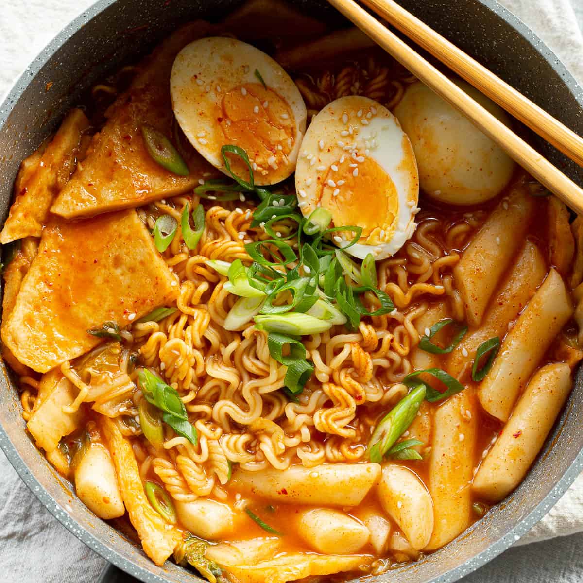 A saucepan filled with rabokki favourites including fish cakes, egg, rice cakes and ramen.
