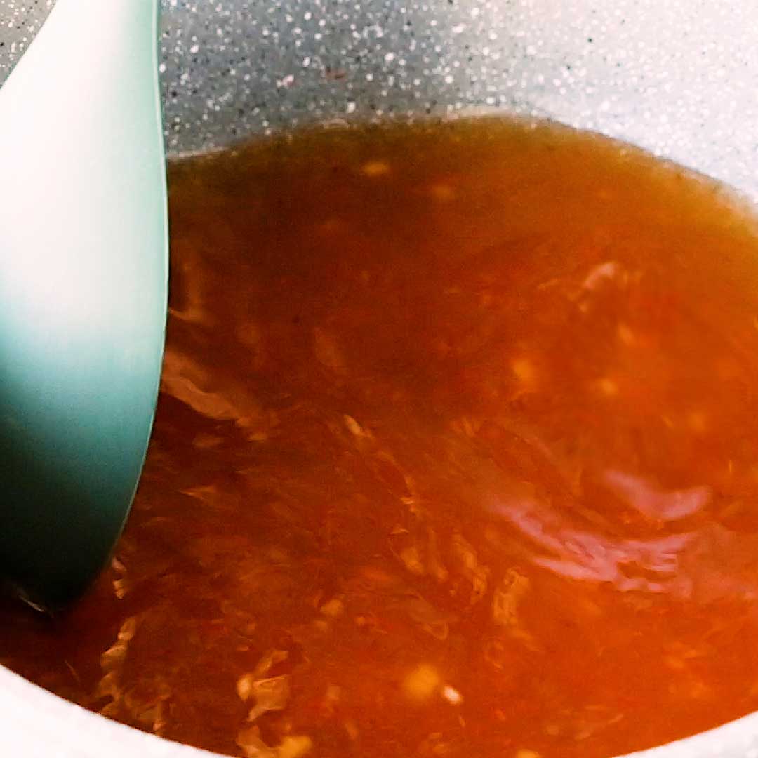 Mixing the sauce with water as it comes to the boil.