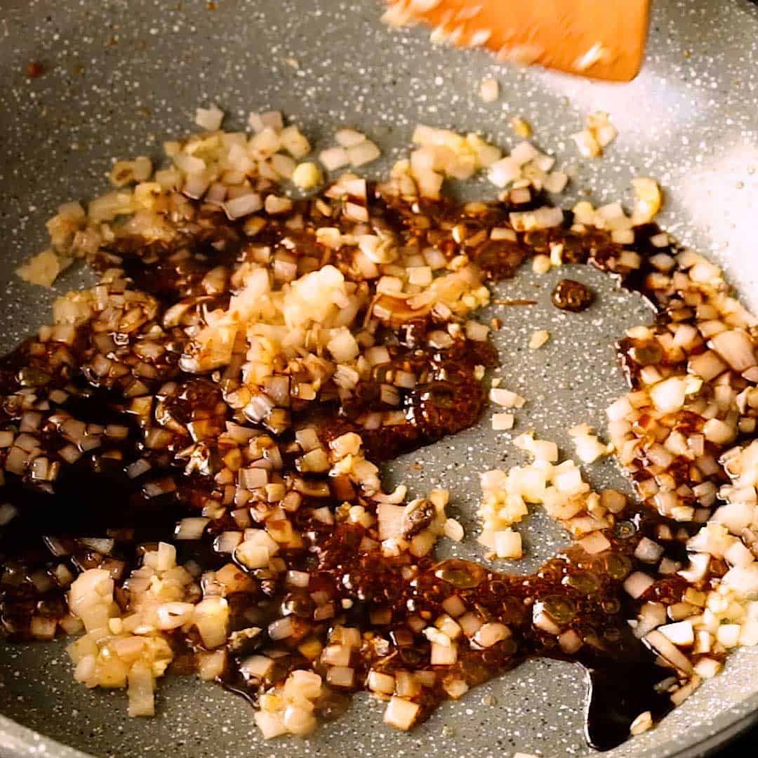 Frying shallot, garlic and kecap manis in a frying pan.