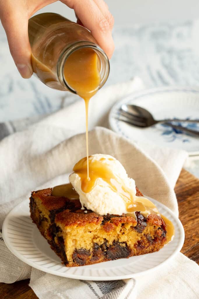 Hot toffee sauce is poured over a slab of sticky date pudding and ice cream.