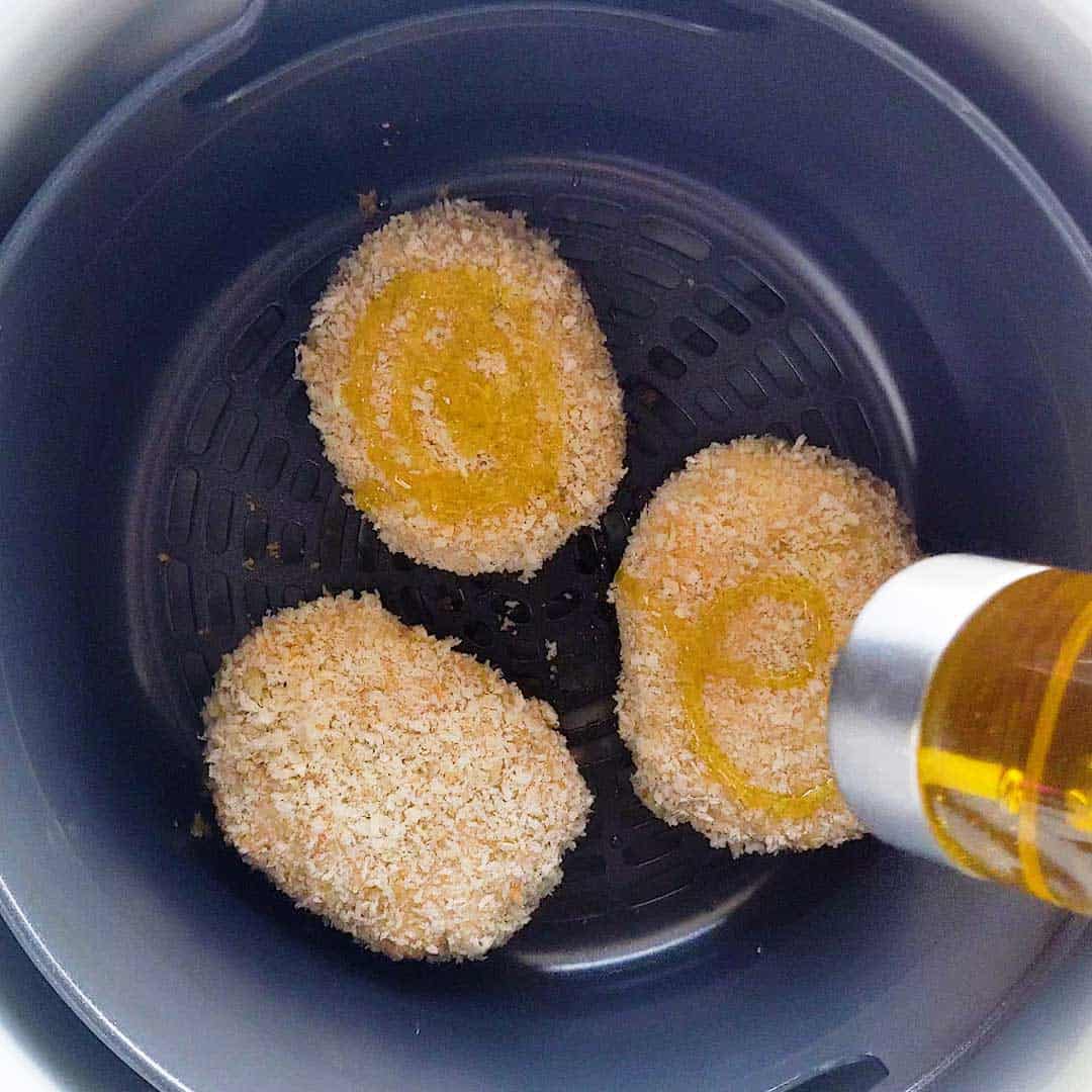 Adding oil to the tops of the korokke to turn golden brown in the air fryer.