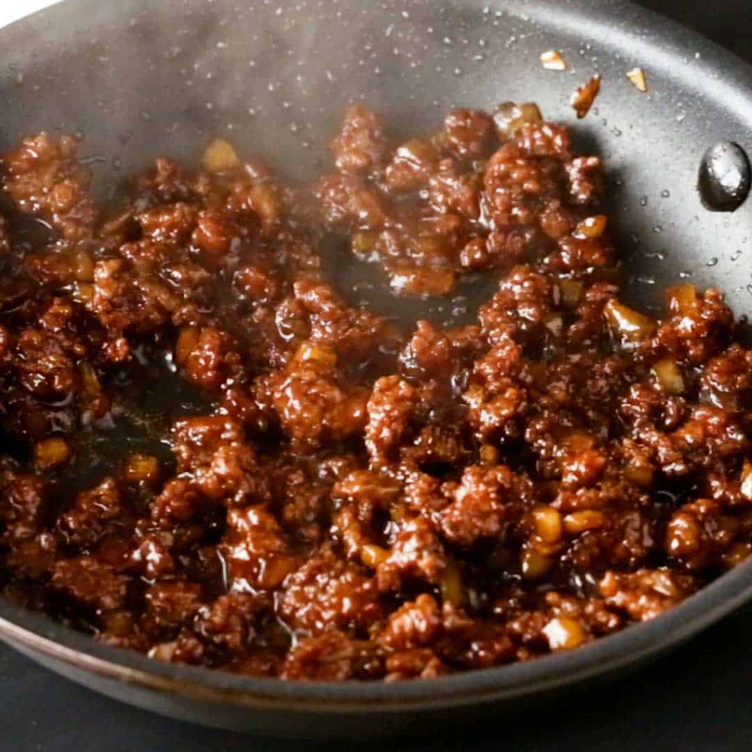 Frying ground beef in a soy sauce, sugar and dashi blend.