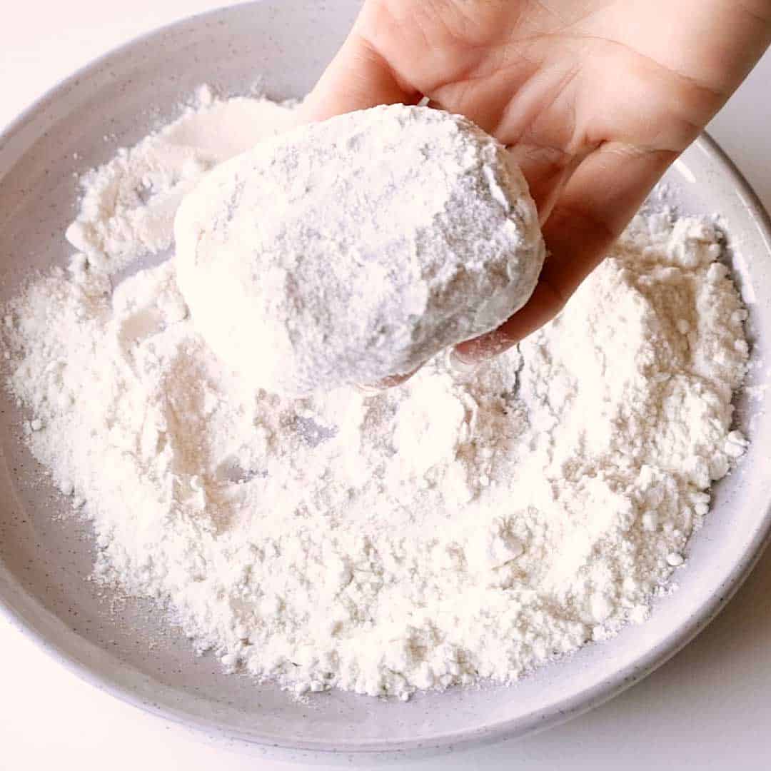 Coating the korokke in flour.