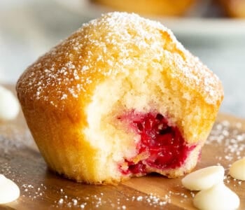 A raspberry muffin with a large bite taken out.