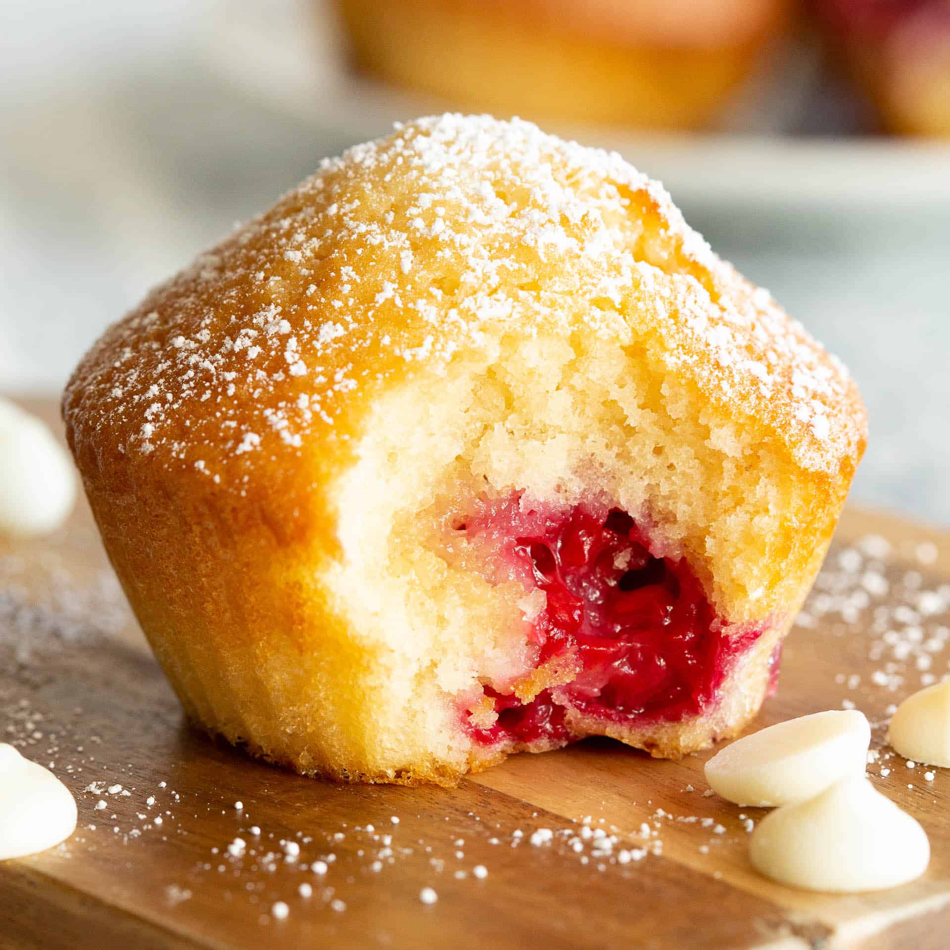 A raspberry muffin with a large bite taken out.