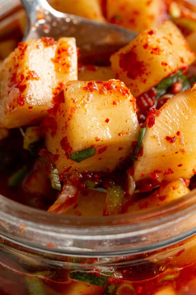 Cubed radish kimchi sit in a small jar, ready to eat.