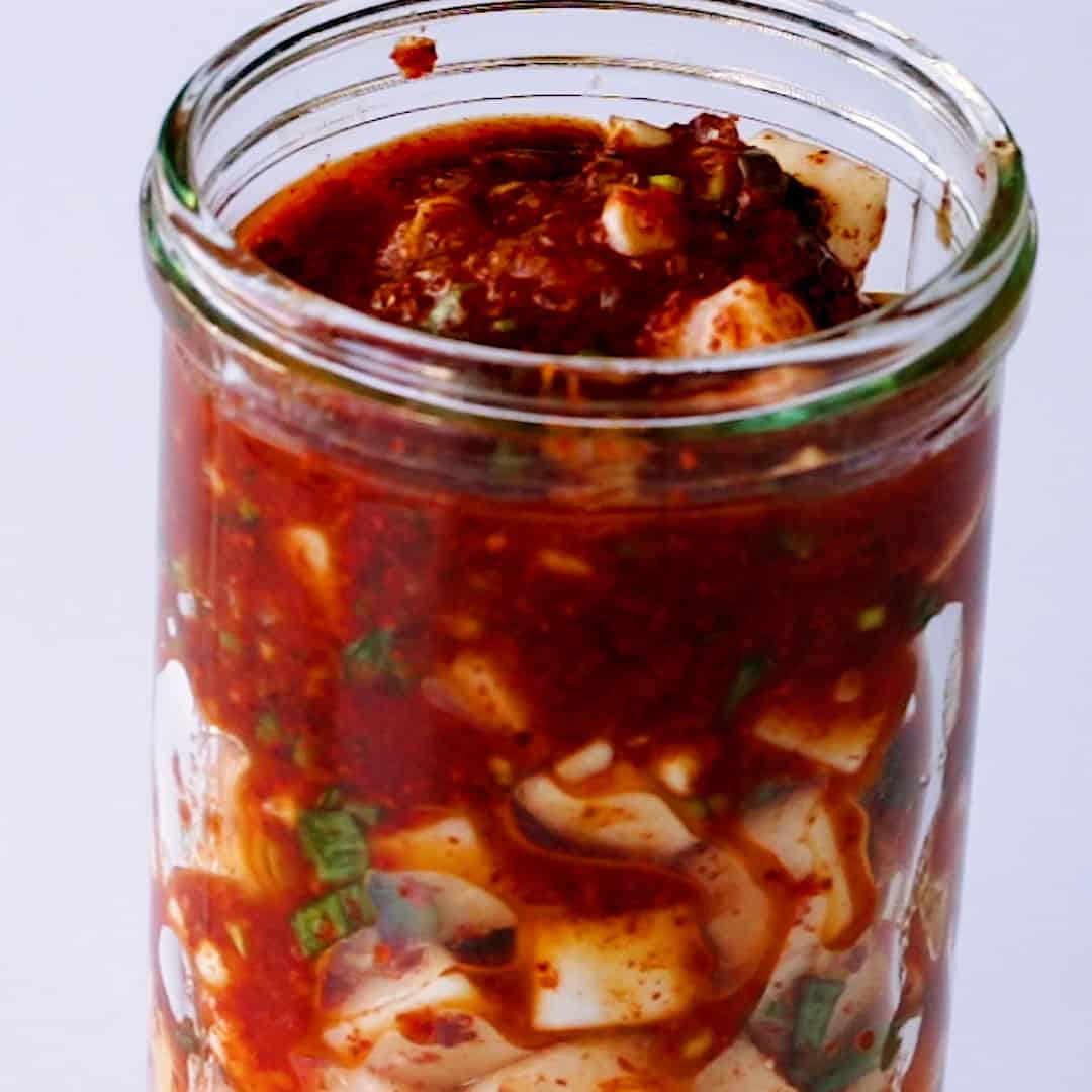 Popping the cubed radish kimchi into a glass jar.