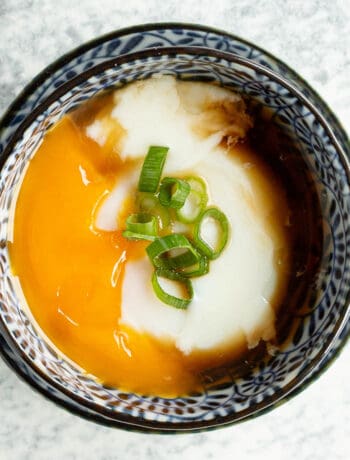 Onsen tamago in a blue bowl with golden yolk oozing out.