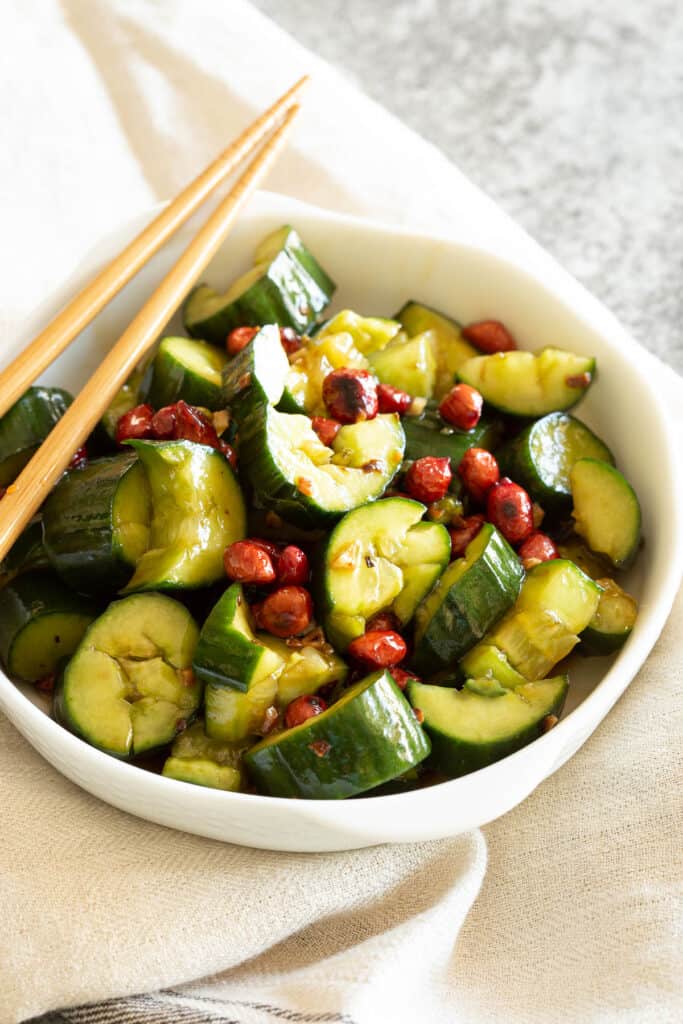 Refreshing smashed cucumber salad in a white bowl with chopsticks.
