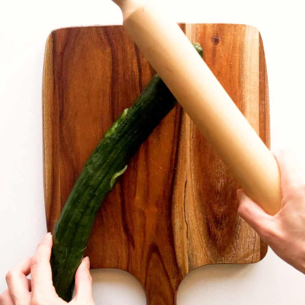 Smashing a cucumber with a rolling pin.