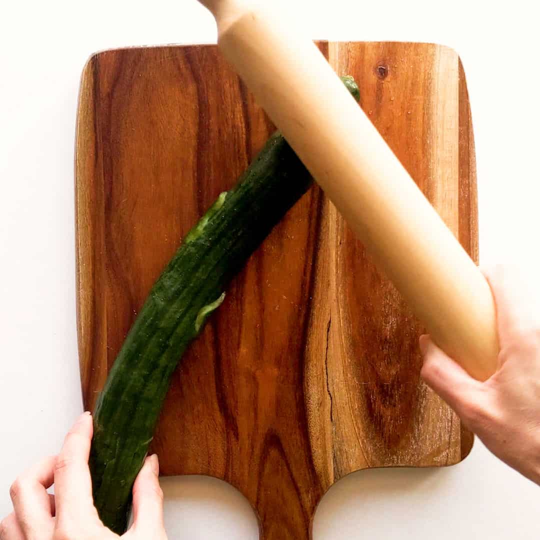 Smashing a cucumber with a rolling pin.