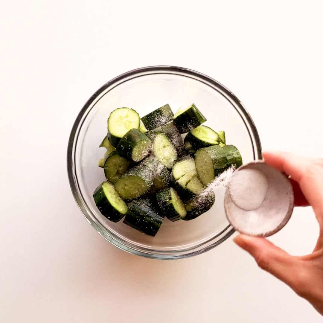 Sprinkling salt over the cucumber.