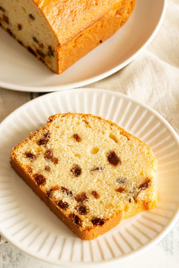 A slice of sultana cake, dotted with plump sultanas throughout.