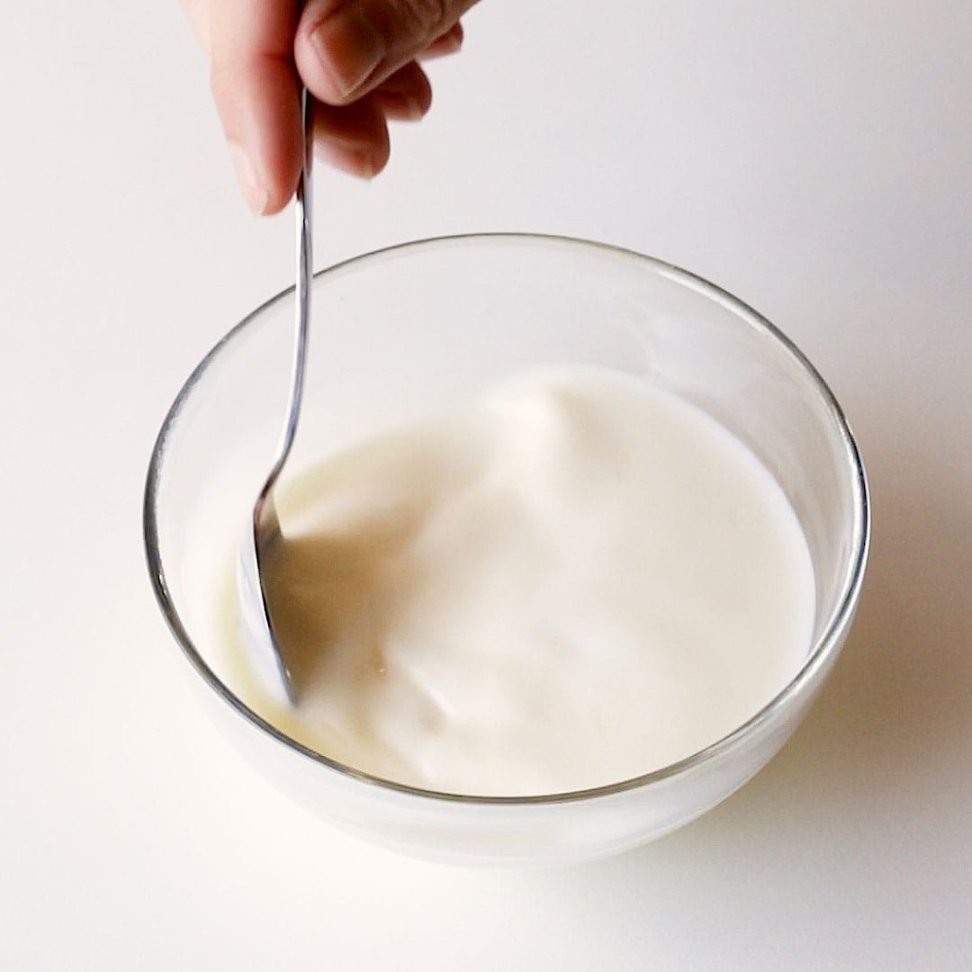 A small spoon stirs milk and lemon juice together.