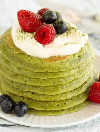 A bright green stack of matcha pancakes with berries and yoghurt on top.