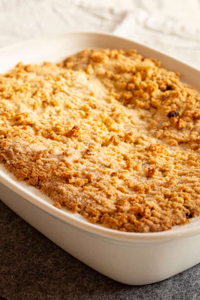 A white baking dish with a golden apple crumble.