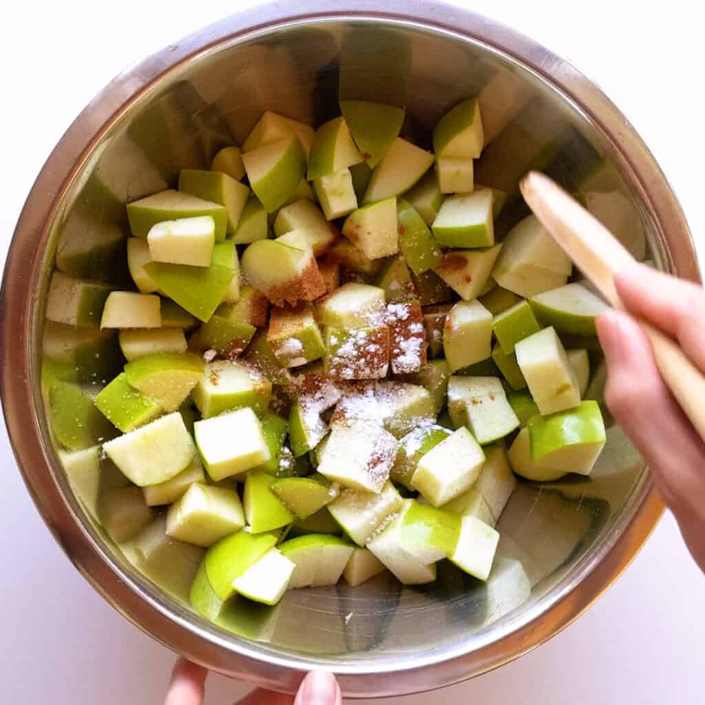 Stirring the cinnamon, sugar and cornstarch through the apple pieces in a large bowl.