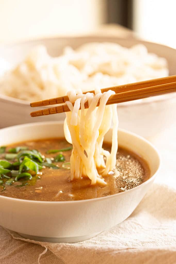 Ramen noodles being dipped into tsukemen sauce.