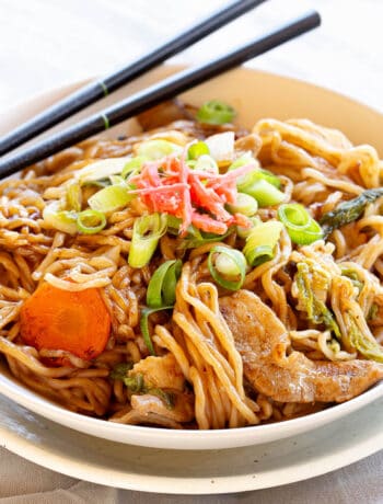 A bowl of yakisoba noodles with a set of chopsticks resting on the rim.