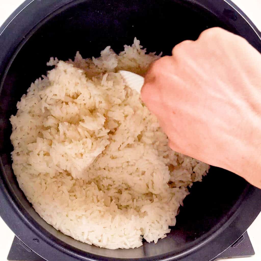 Fluffing the rice with a paddle in rice cooker.