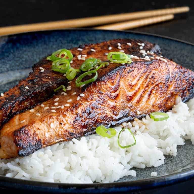 Miso glazed salmon on a bed of rice, garnished with spring onion.