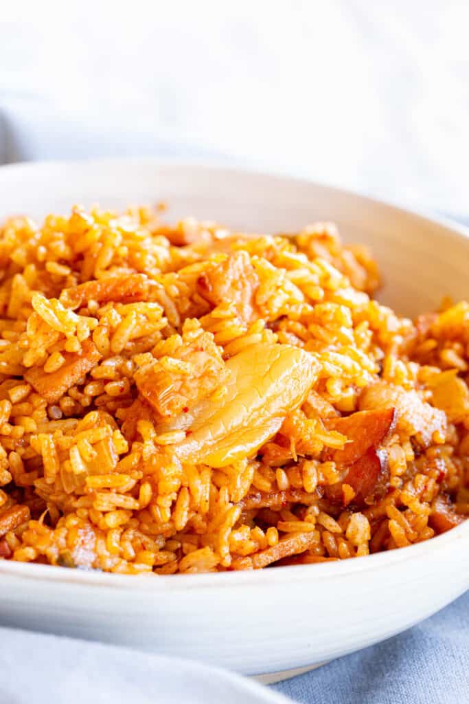 A white bowl filled with red spicy kimchi fried rice.