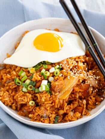 A white bowl on a blue tea towel filled with Korean fried rice and fried egg.