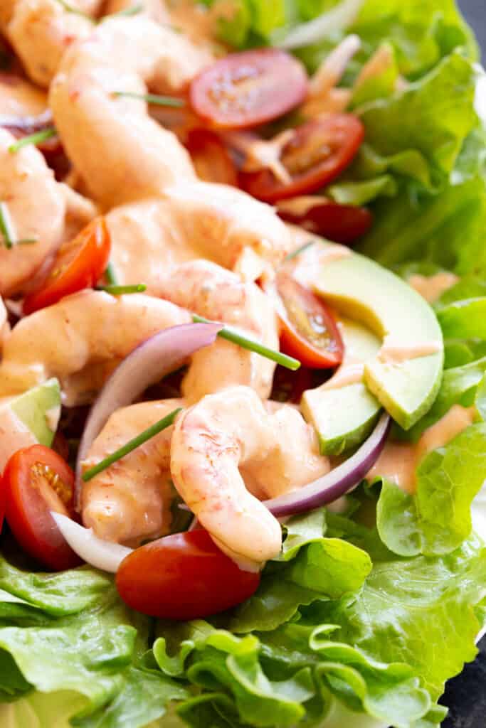 A colourful array of prawns, avocado, tomato, onion and lettuce on a platter.