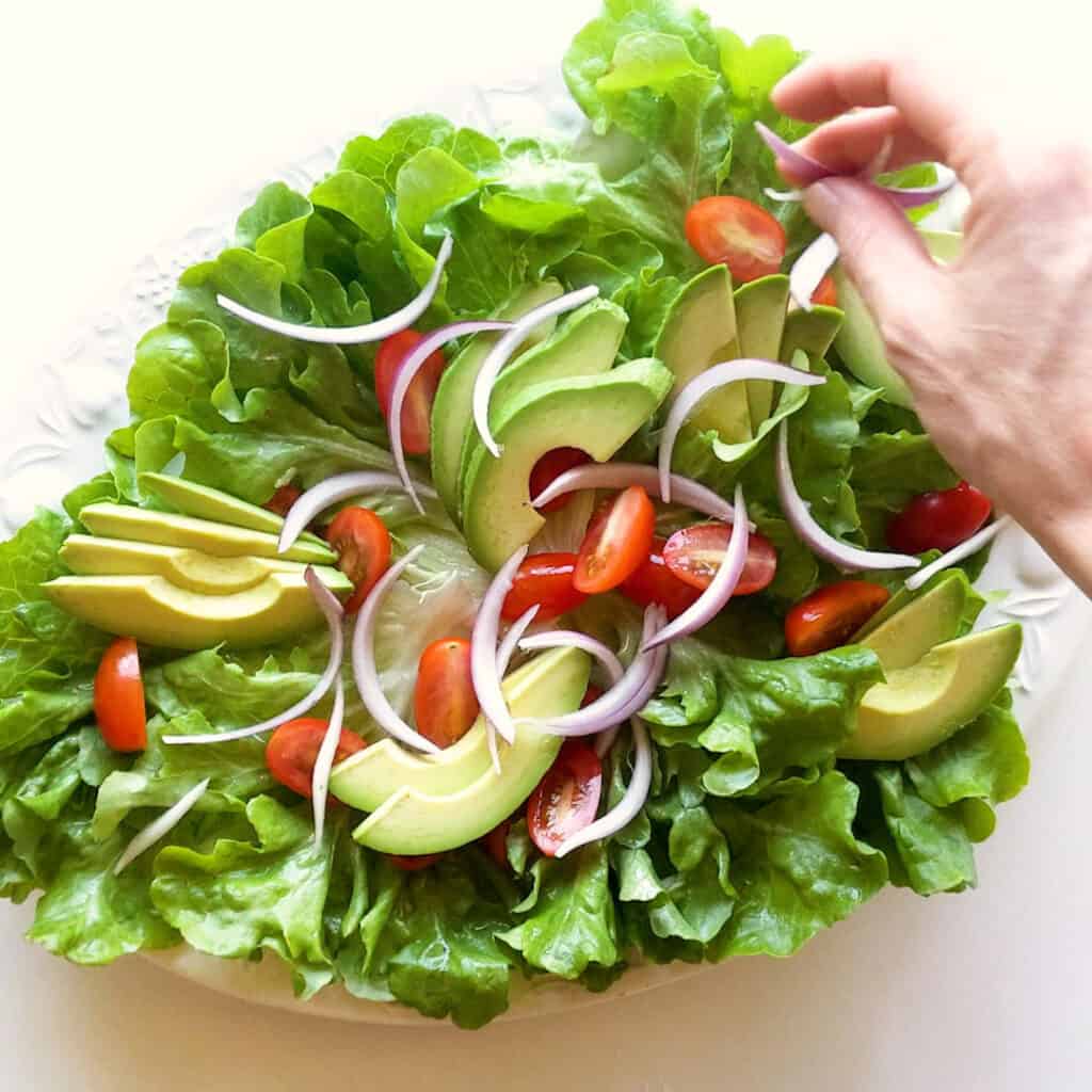 Arranging the salad on a white platter.
