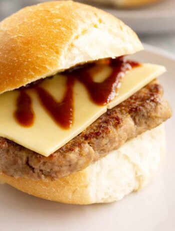 Scottish breakfast bun with Lorne sausage and cheese on a white plate.