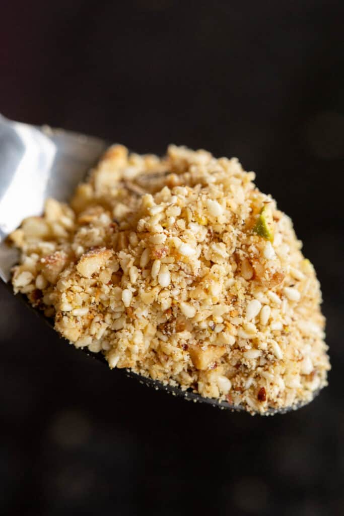 A spoon holds up a mound of freshly made dukkah.