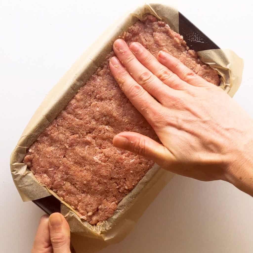 Pressing the meat mixture into the loaf pan.