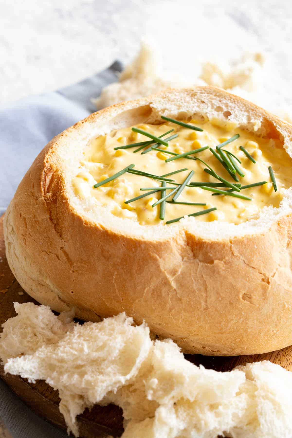 A golden, creamy chicken and corn cob loaf dip with a garnish of fresh chives.