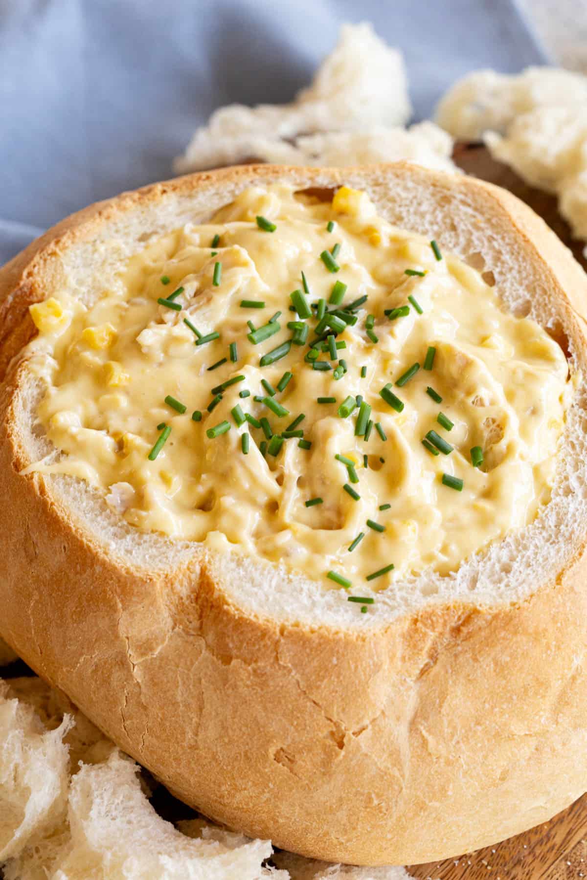 A chicken and corn dip in a cob loaf with chives for garnish.