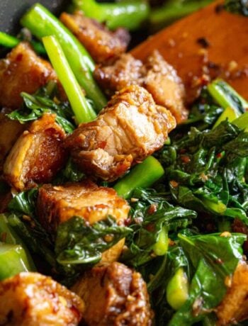 Chinese broccoli and crispy pork stir fry in a frying pan.