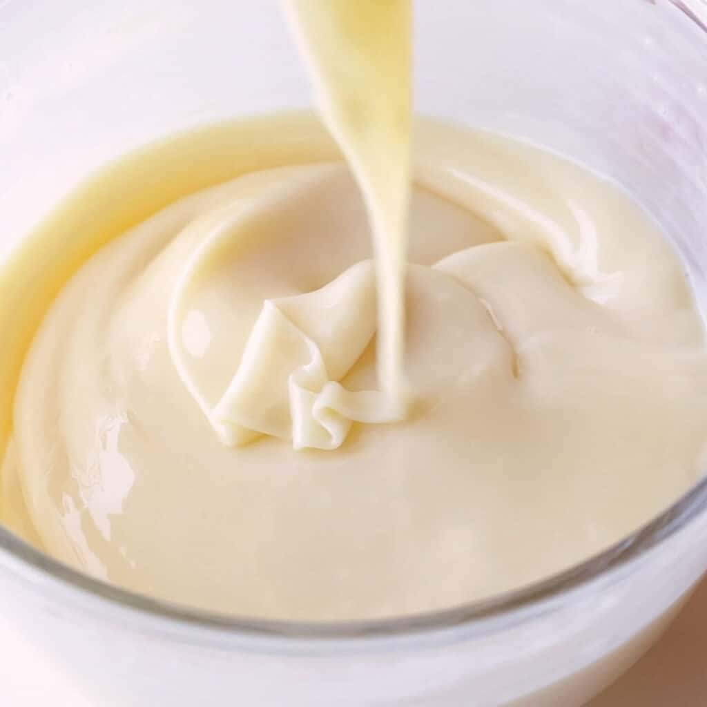 Lemon juice and condensed milk being mixed together with the boiling gelatin mix.