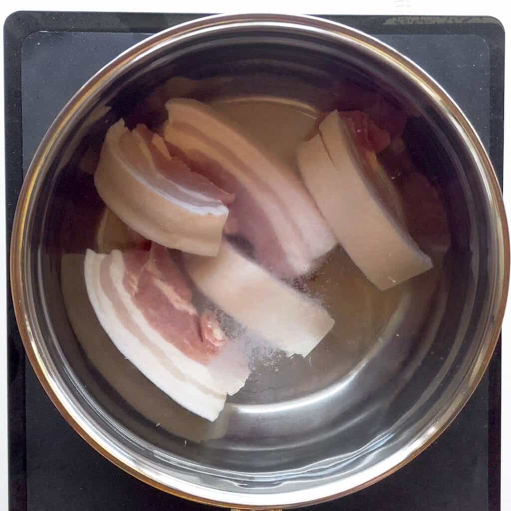 Boiling the pork strips in a saucepan.