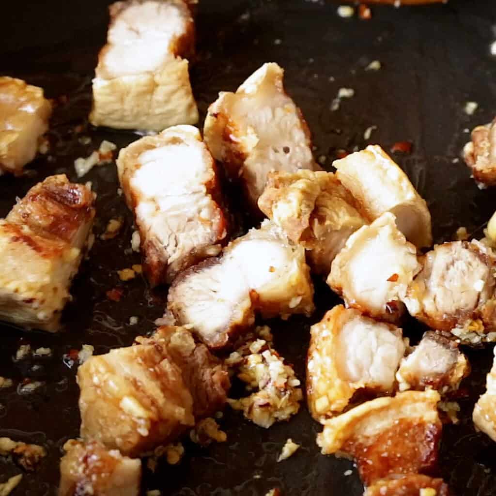 Frying pork belly pieces in chilli and garlic.