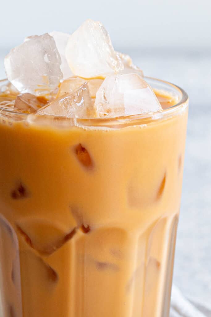 A glass filled to the brim with Thai iced tea.
