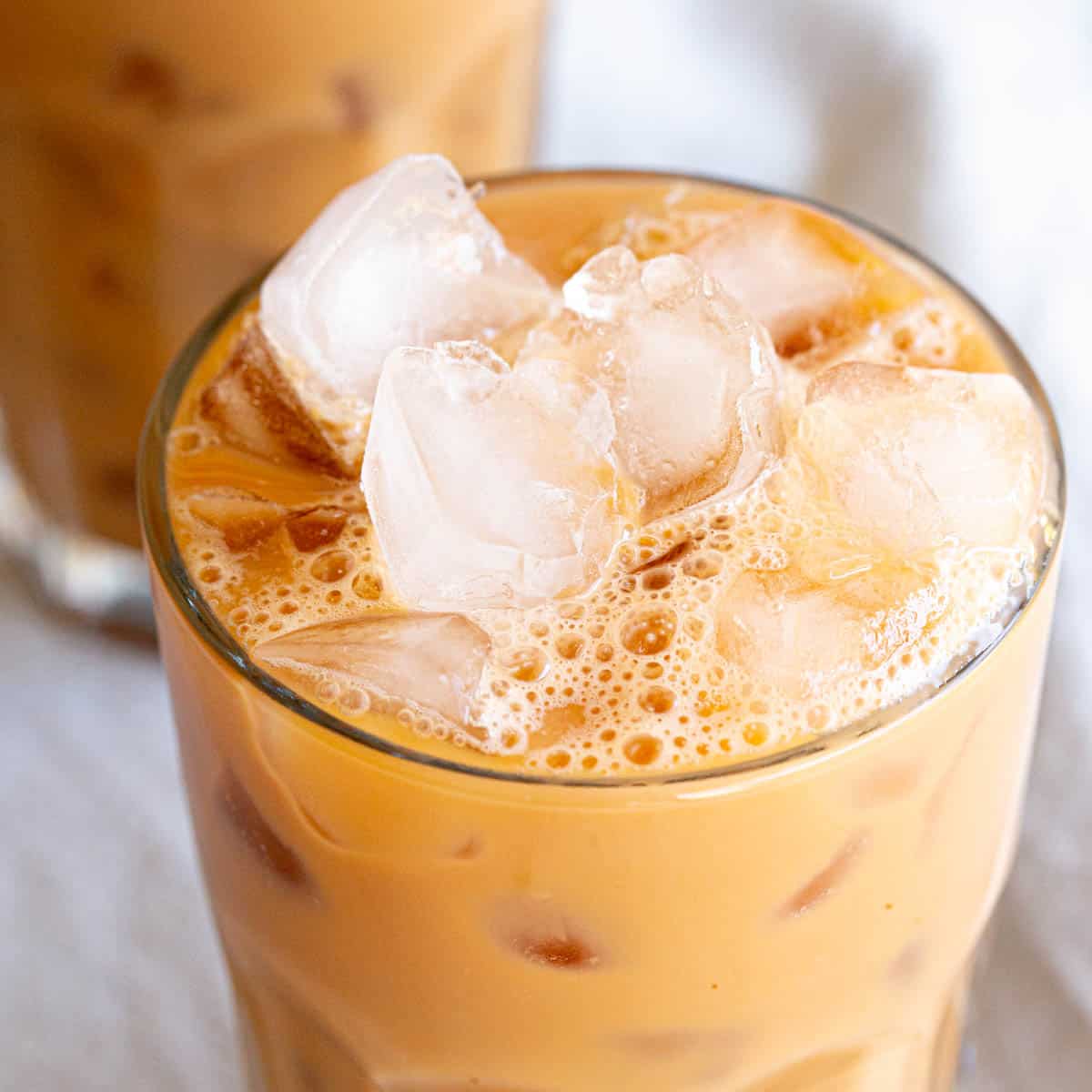 A frosty glass of Thai iced tea with ice cubes.