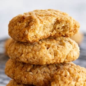 A stack of Anzac biscuits. The top biscuit has a bite taken out of it.