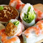Rice paper roll cut in half and dipped in peanut hoisin sauce.