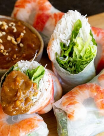 Rice paper roll cut in half and dipped in peanut hoisin sauce.