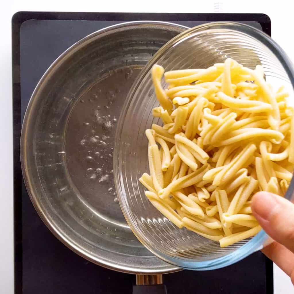 Pouring pasta into a saucepan.