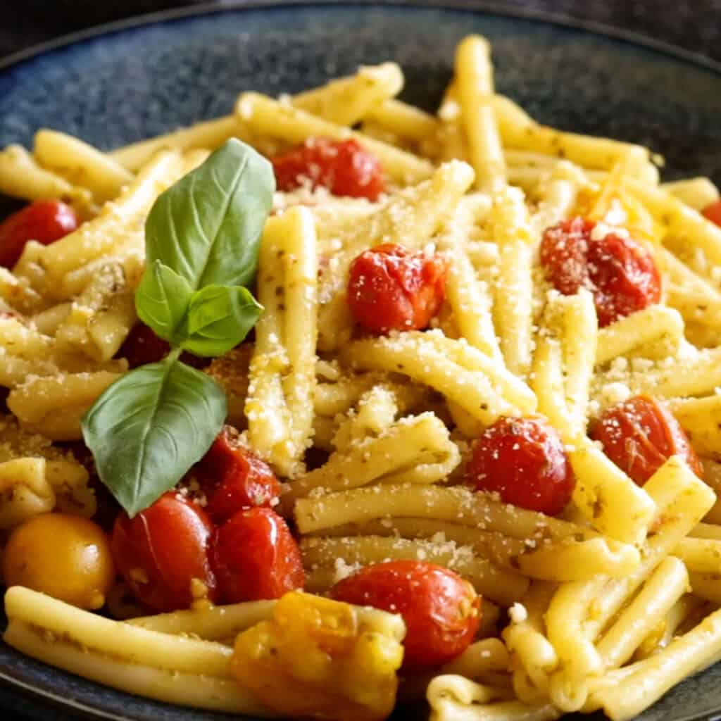 Fresh basil and parmesan is garnished over the top of the cherry tomato pesto pasta.