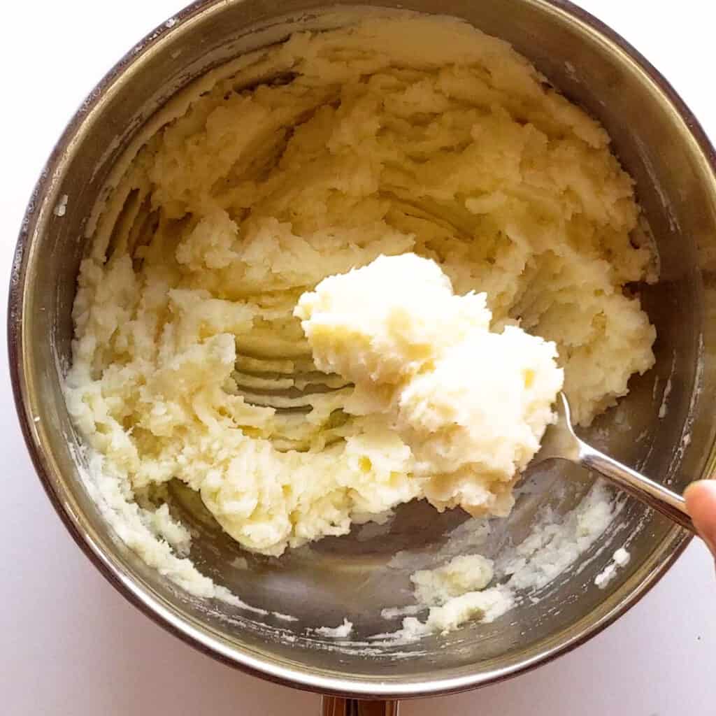 Whipping the mash potato with a fork for extra fluffiness.